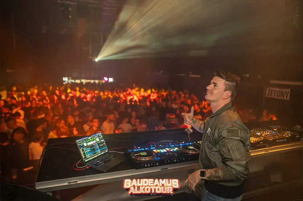 DJ u pultu před rozjetým sálem